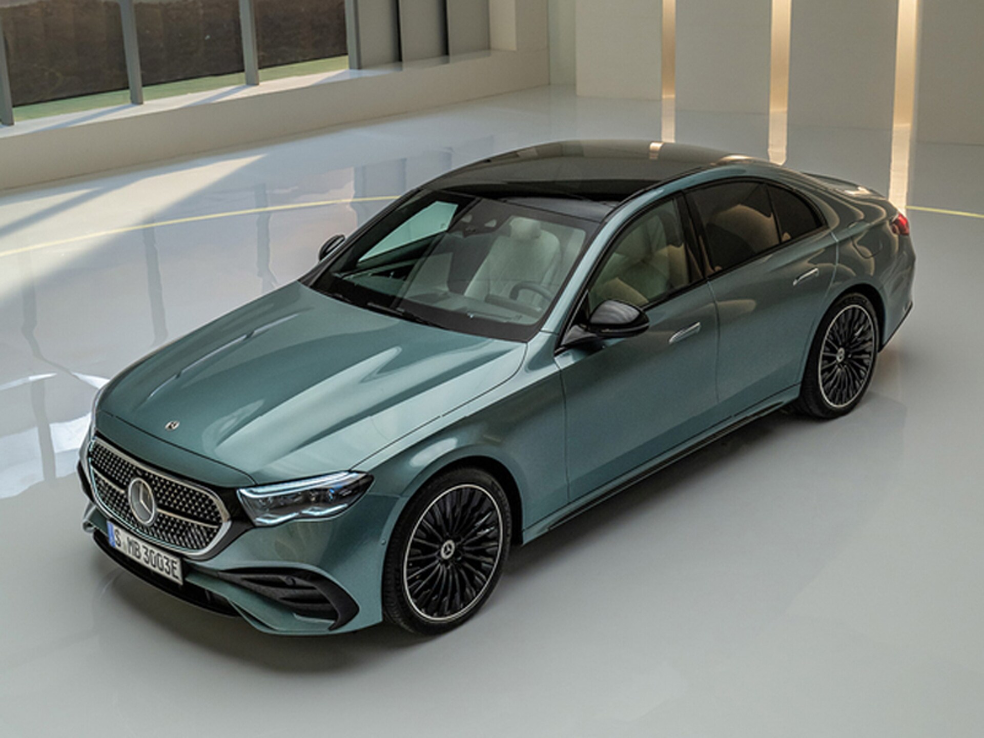 Fahrzeug-Angebote | Mercedes-Benz. Eine grüne Mercedes-Benz E-Klasse Limousine steht in einem hell beleuchteten, weißen Raum.
