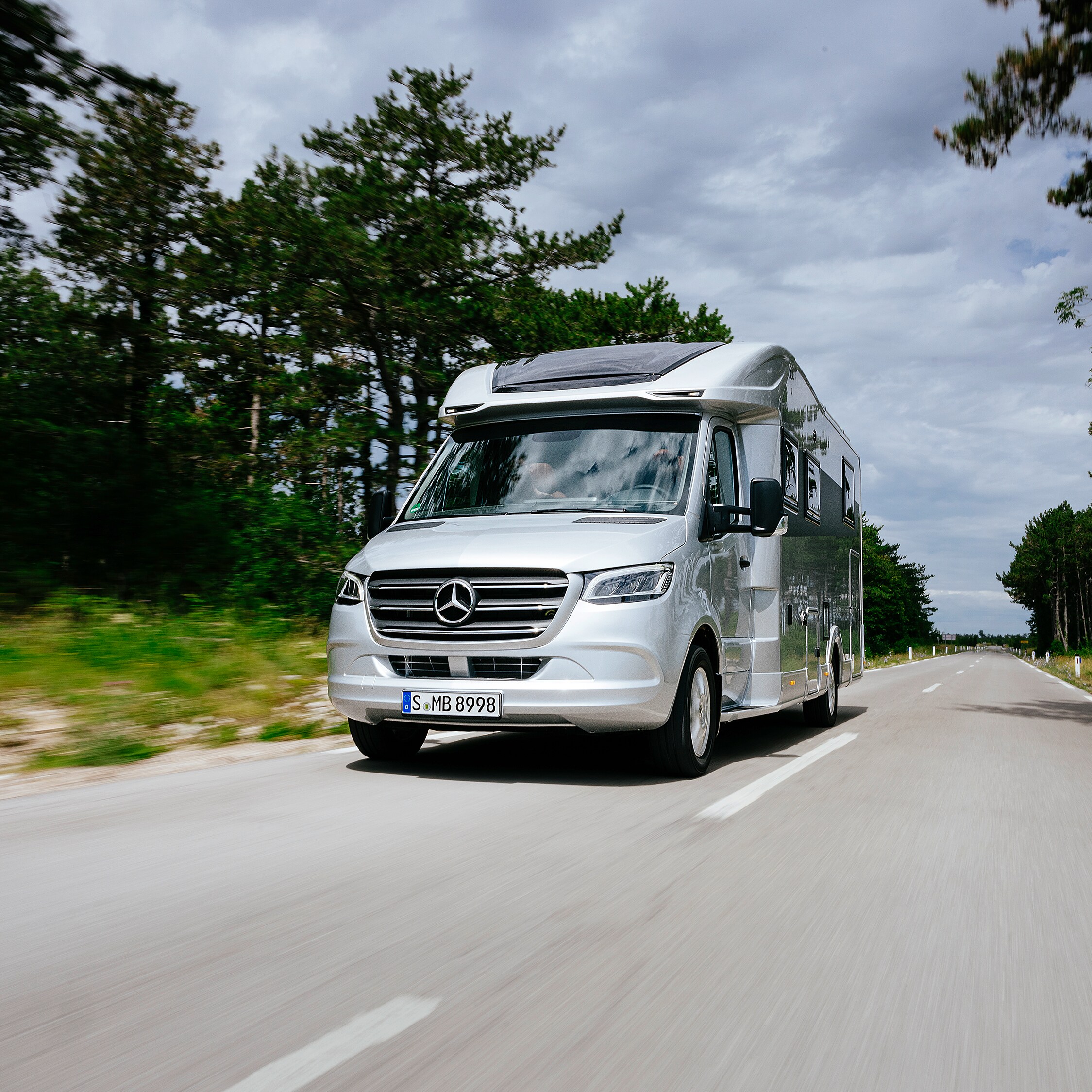 Der Sprinter – Variantenvielfalt für Ihre Reisemobil-Basis. Ein Sprinter Fahrgestell als Basis mit einem gezeichneten Reisemobil Aufbau steht in einer Fabrikhalle.