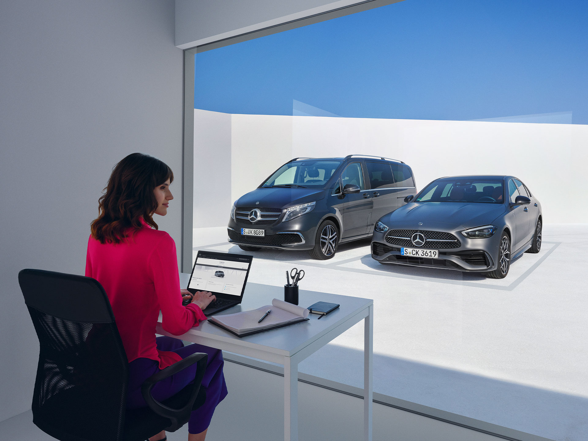 Digitale Extras | Mehr erfahren | Mercedes-Benz Frauen, die vor der Mercedes-Benz V-Klasse und C-Klasse sitzen und auf einen Laptop schauen.