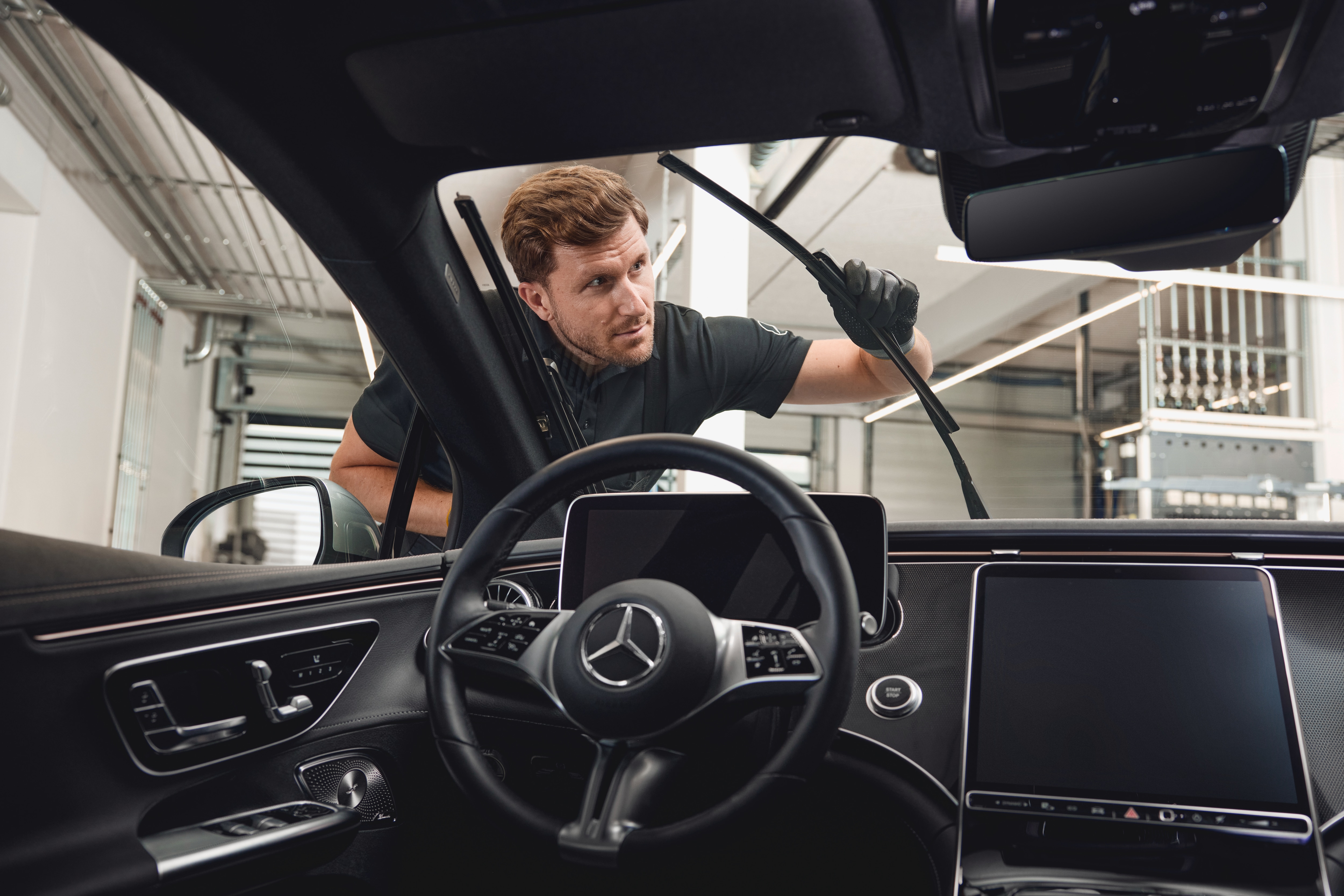 Ersatzteile | Mercedes-Benz Innenansicht eines Mercedes-Benz-Fahrzeugs, in dem ein Techniker Original-Scheibenwischerblätter austauscht.