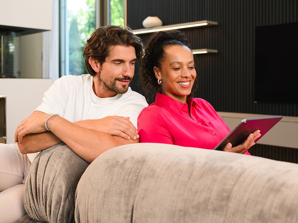 Mercedes-Benz Financial Services im Überblick | Aktuelle Angebote Zwei Menschen auf der Couch schauen auf ein Tablet.