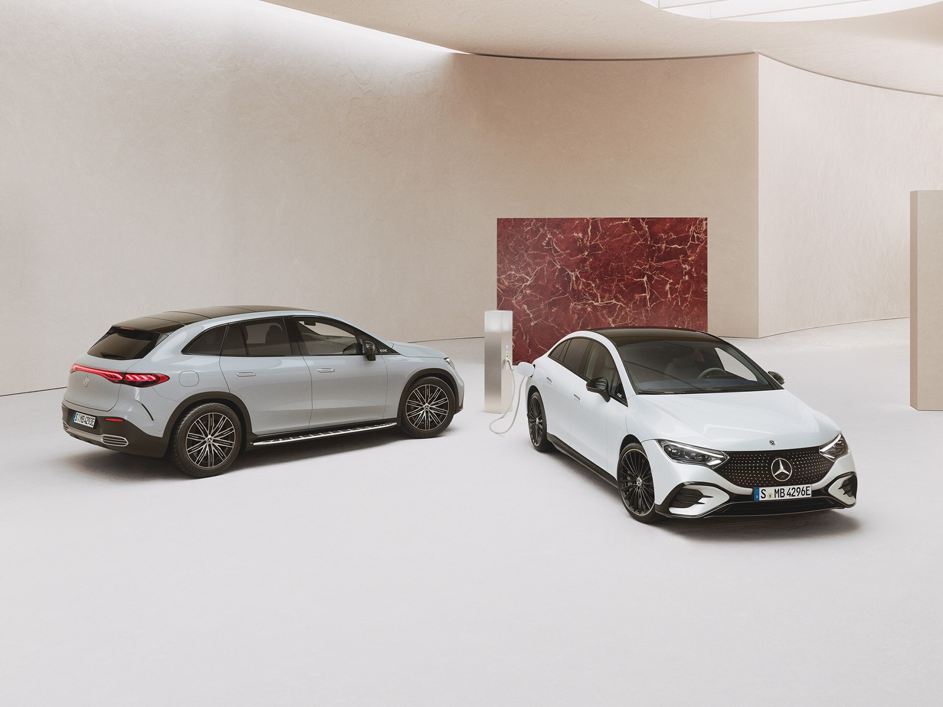 Elektroauto Förderung | Mercedes-Benz Mercedes-Benz EQE Limousine und SUV parkend in einem Showroom vor hellem Hintergrund.