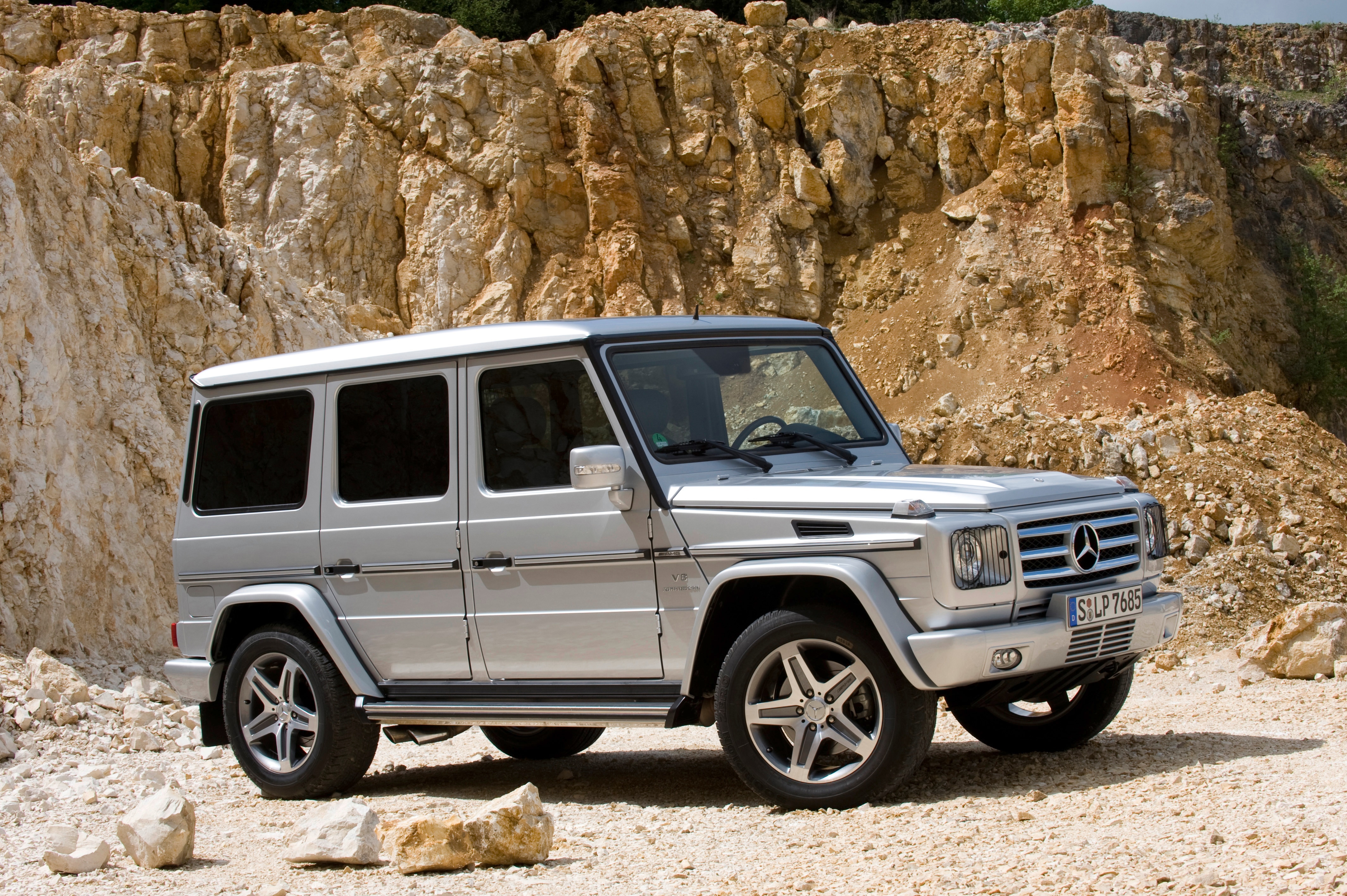 Service- und Garantiepakete | Mercedes-Benz. Eine silberne G-Klasse von Mercedes-Benz steht in der Sonne vor einer Felswand.
