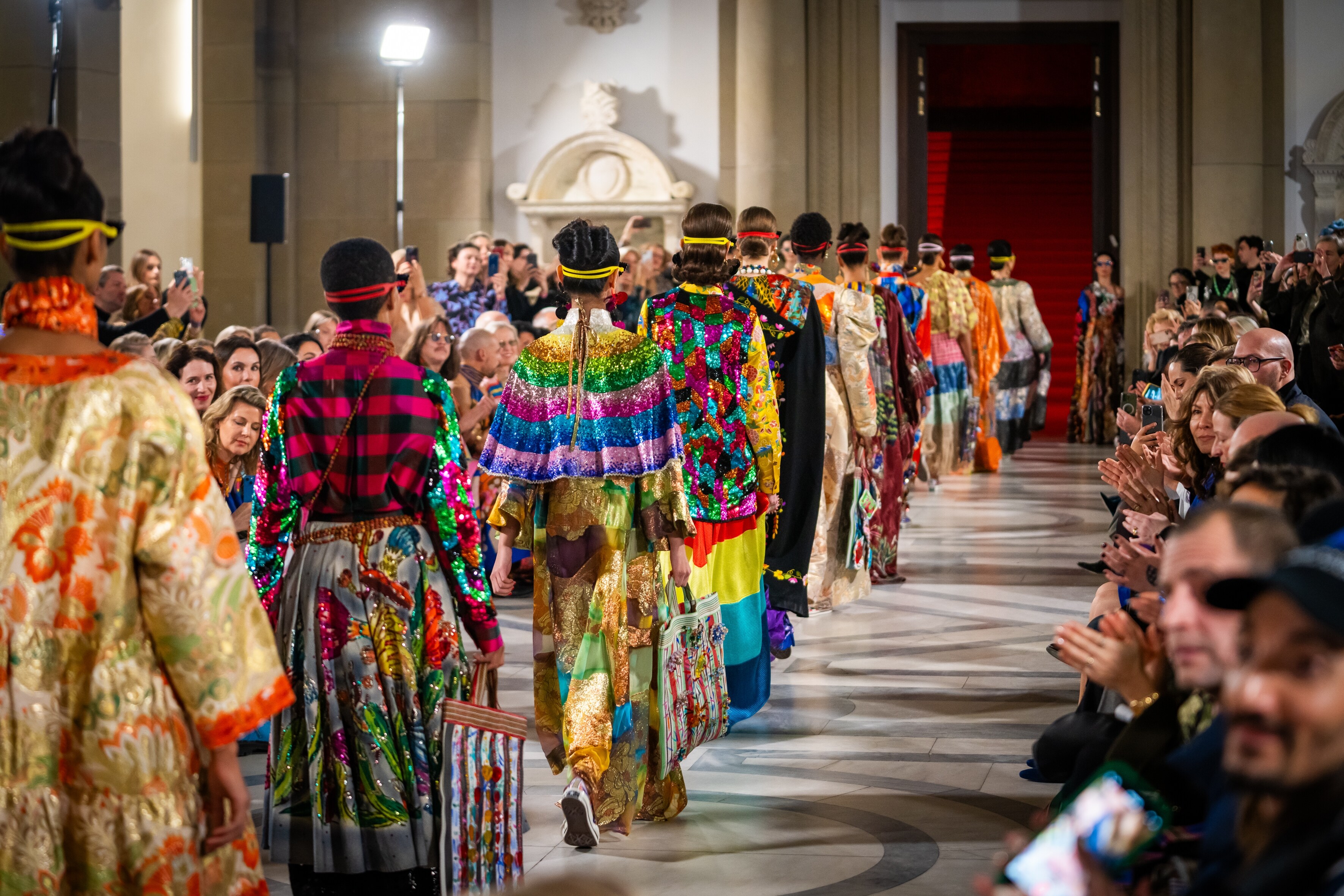Ein Model auf einem Laufsteg der Mercedes-Benz Fashion Moments Viele Models auf einem Laufsteg der Mercedes-Benz Fashion Moments in farbenfrohen Outfits.