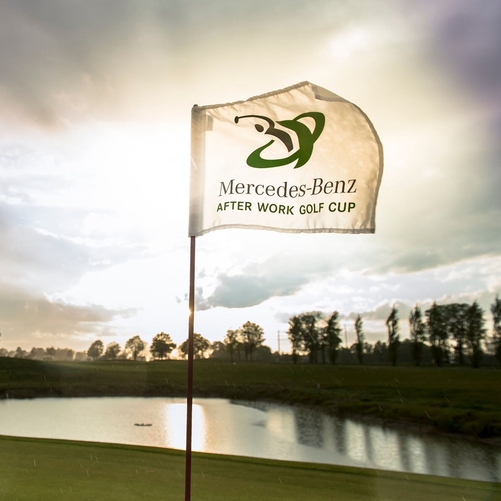 Golf | Mercedes-Benz Ein Golfplatz mit einer wehenden Fahne im Sonnenlicht.
