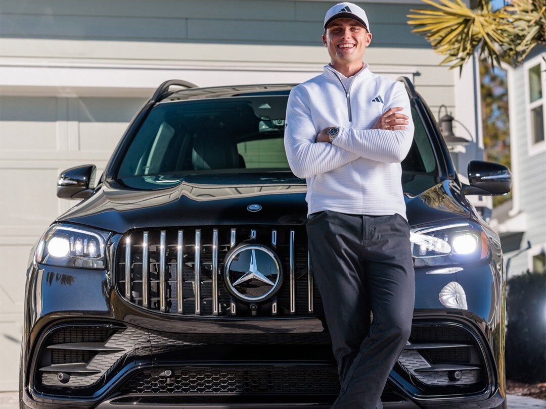 Golf | Mercedes-Benz Ein Mann (Ludvig Aberg) lehnt an seinem Auto und lächelt.