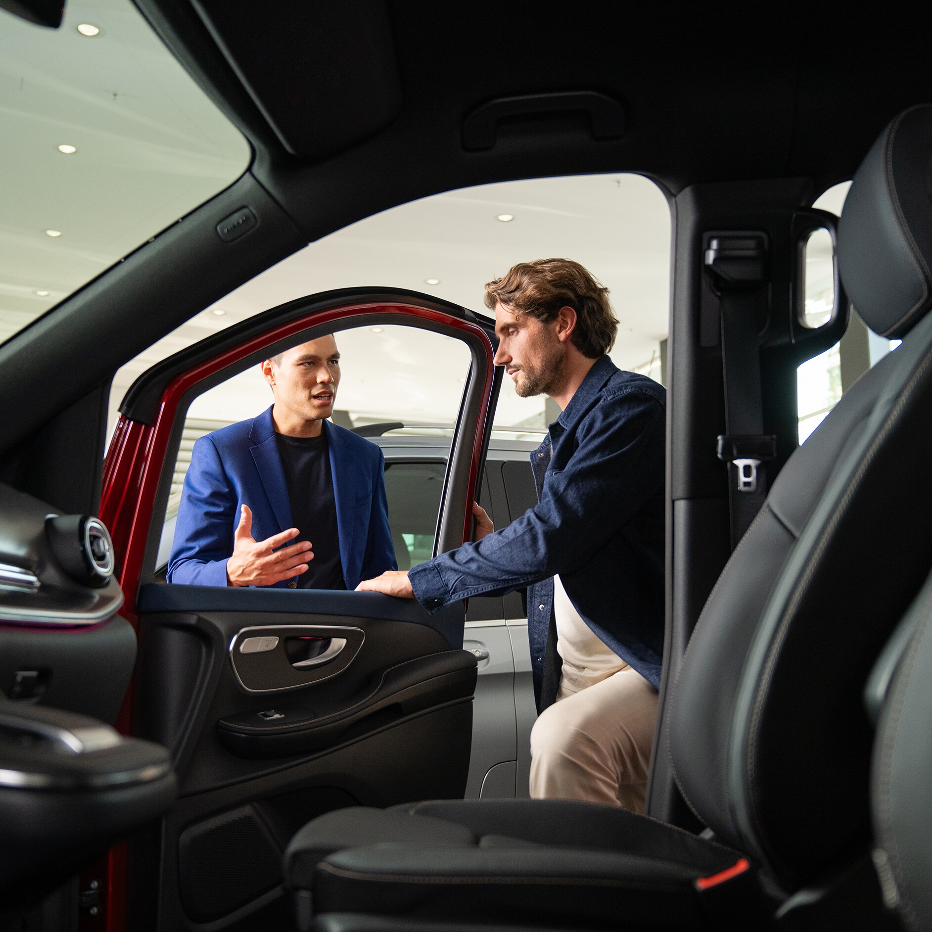 Mercedes-Benz Kontakt Leasing, Finanzierung und Versicherung Innenansicht eines Mercedes-Benz Transporters mit Blick auf zwei sich unterhaltenden Personen an der geöffneten Tür.