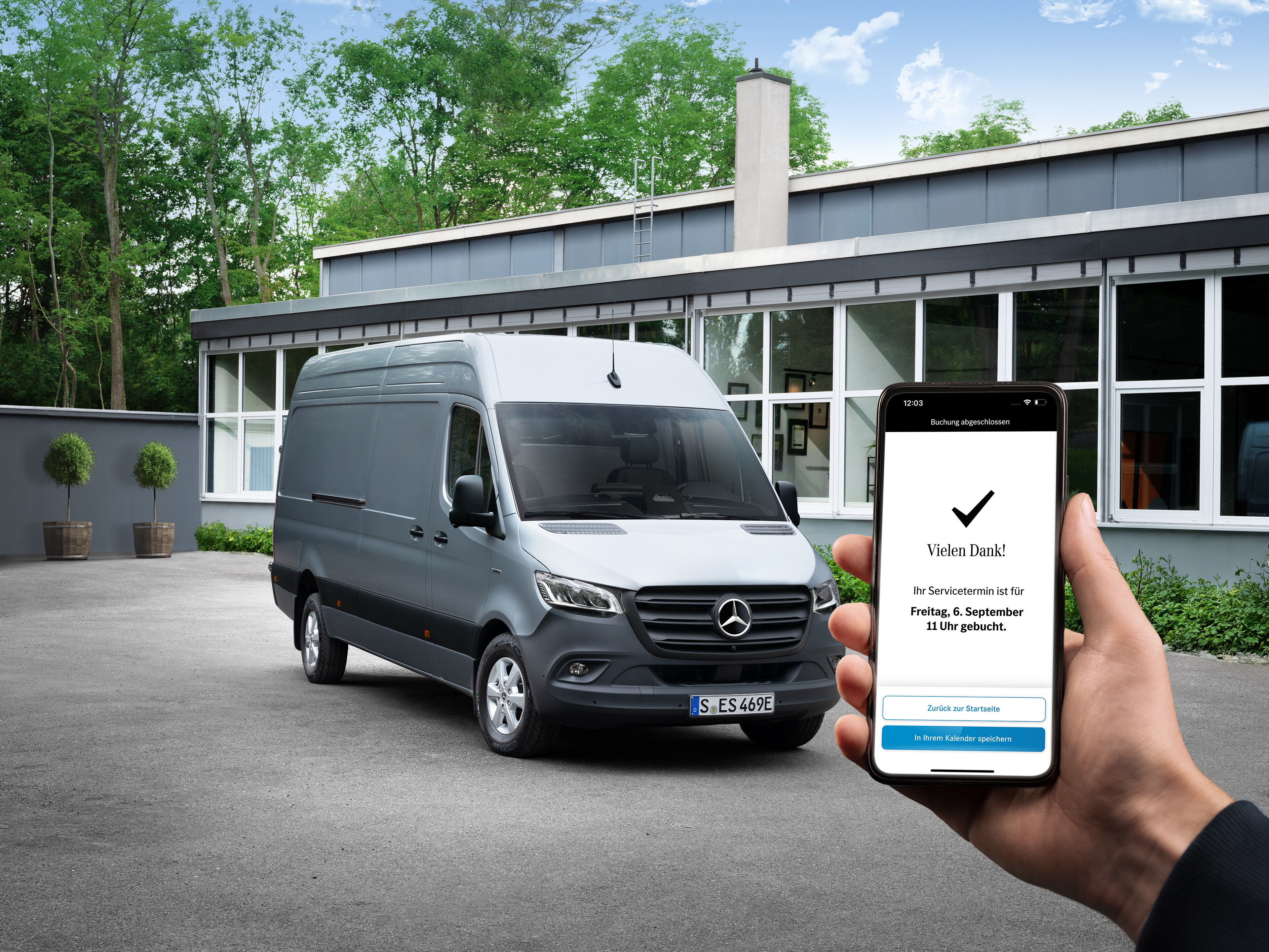 Mercedes-Benz Online-Terminbuchung Ein Hand hält ein Smartphone in den Händen. Im Hintergrund steht ein Mercedes-Benz Transporter.