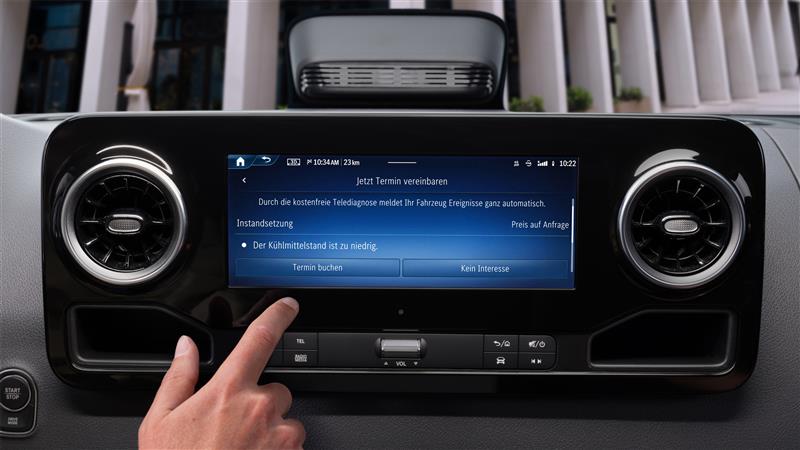 Onboard Service App | Mercedes-Benz Transporter. Finger tippt im Auto auf den Bildschirm, um einen Termin über die Mercedes-Benz Service App zu buchen.