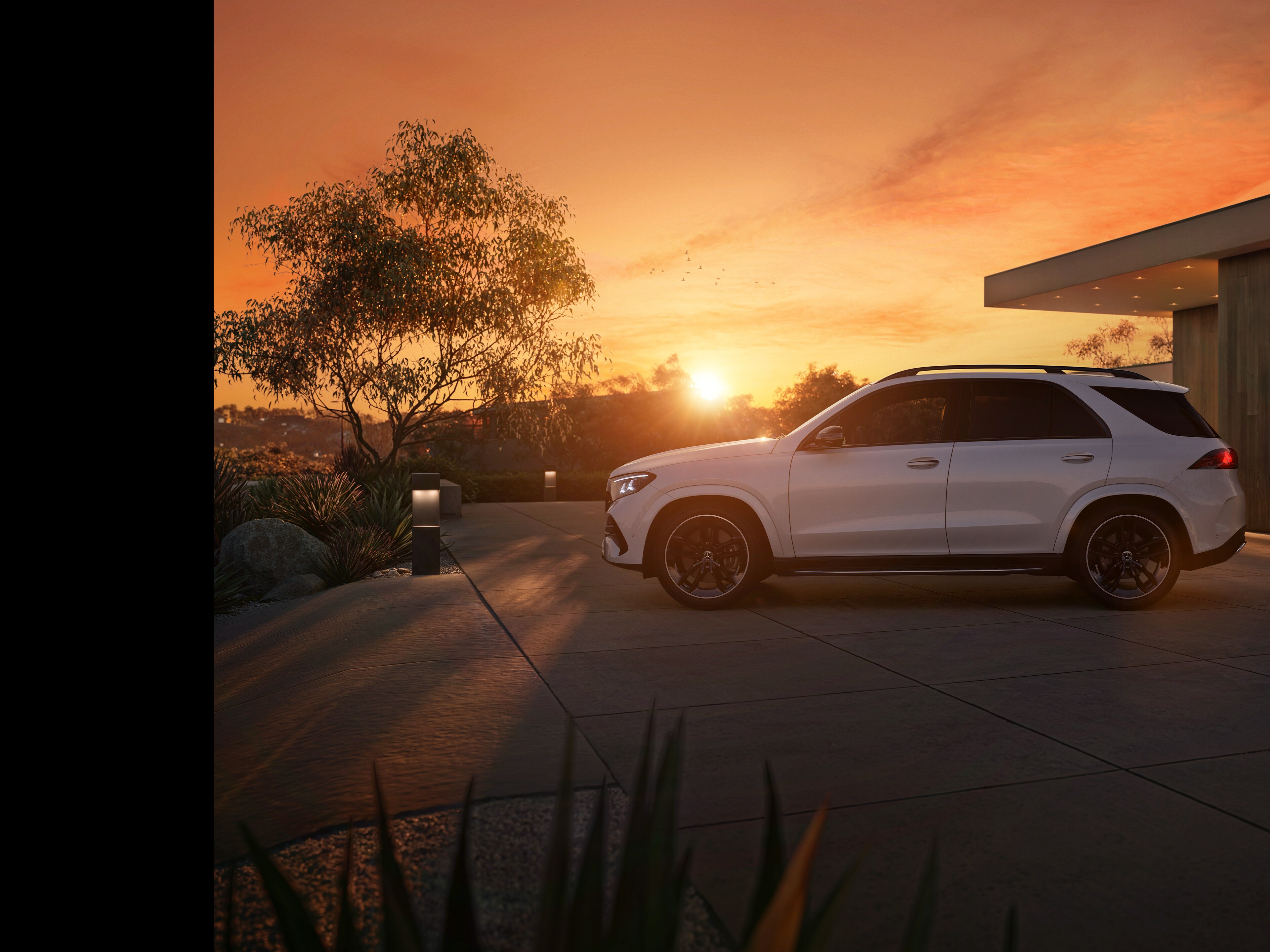 Der neue Mercedes-Benz GLE SUV, seitlicher Frontansicht parkend vor einem Haus bei Sonnenuntergang