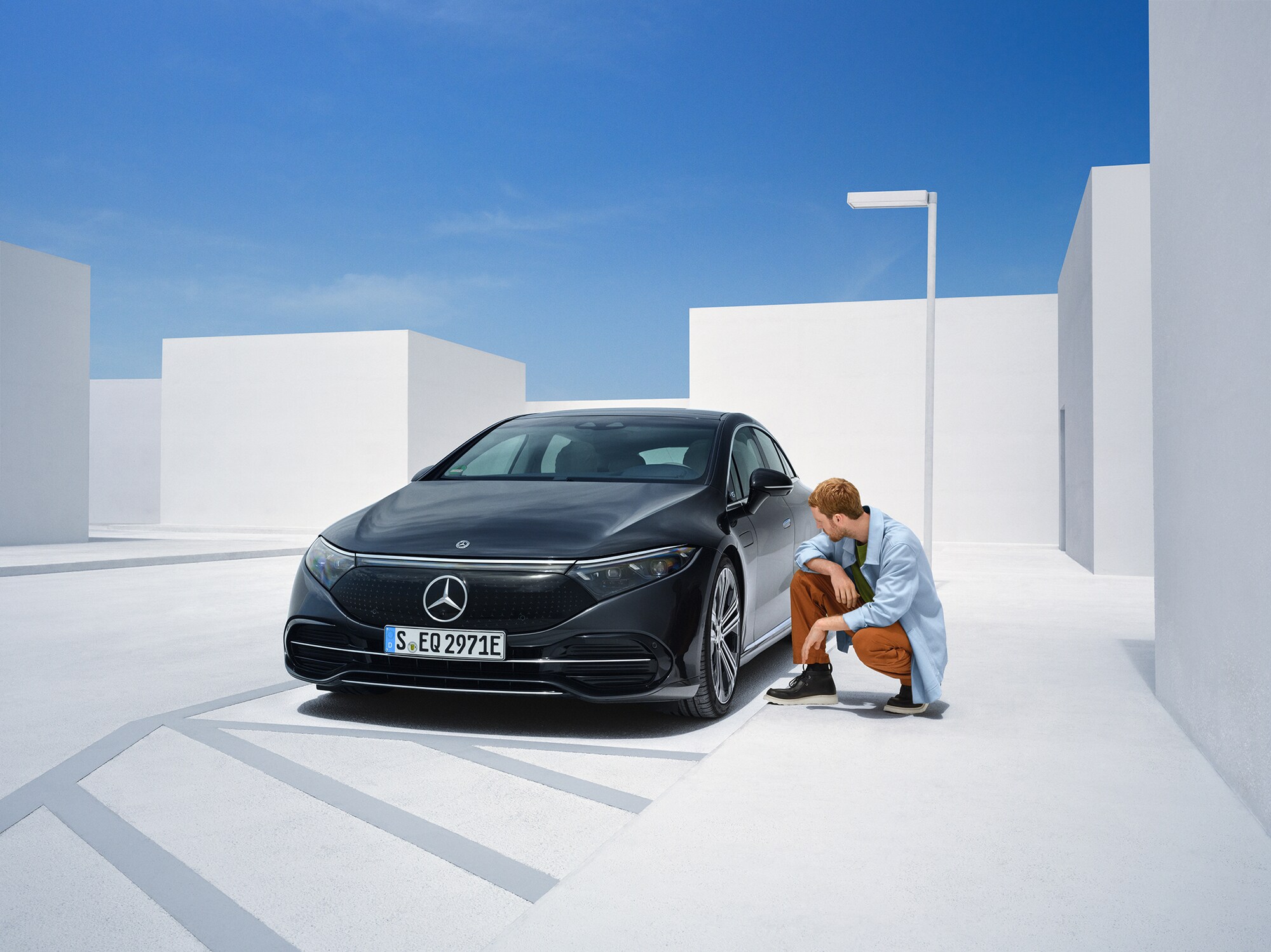 Schadensmeldung | Mercedes-Benz Ein Mann kniet neben seinem Mercedes-Benz, um ihn zu überprüfen