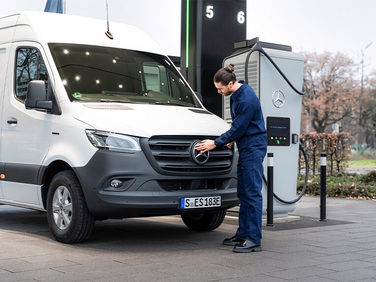 Ladelösungen für elektrische Transporter von Mercedes-Benz Eine Person vor einem weißen Mercedes-Benz Sprinter öffnet die Lade-Steckdose des Fahrzeugs.