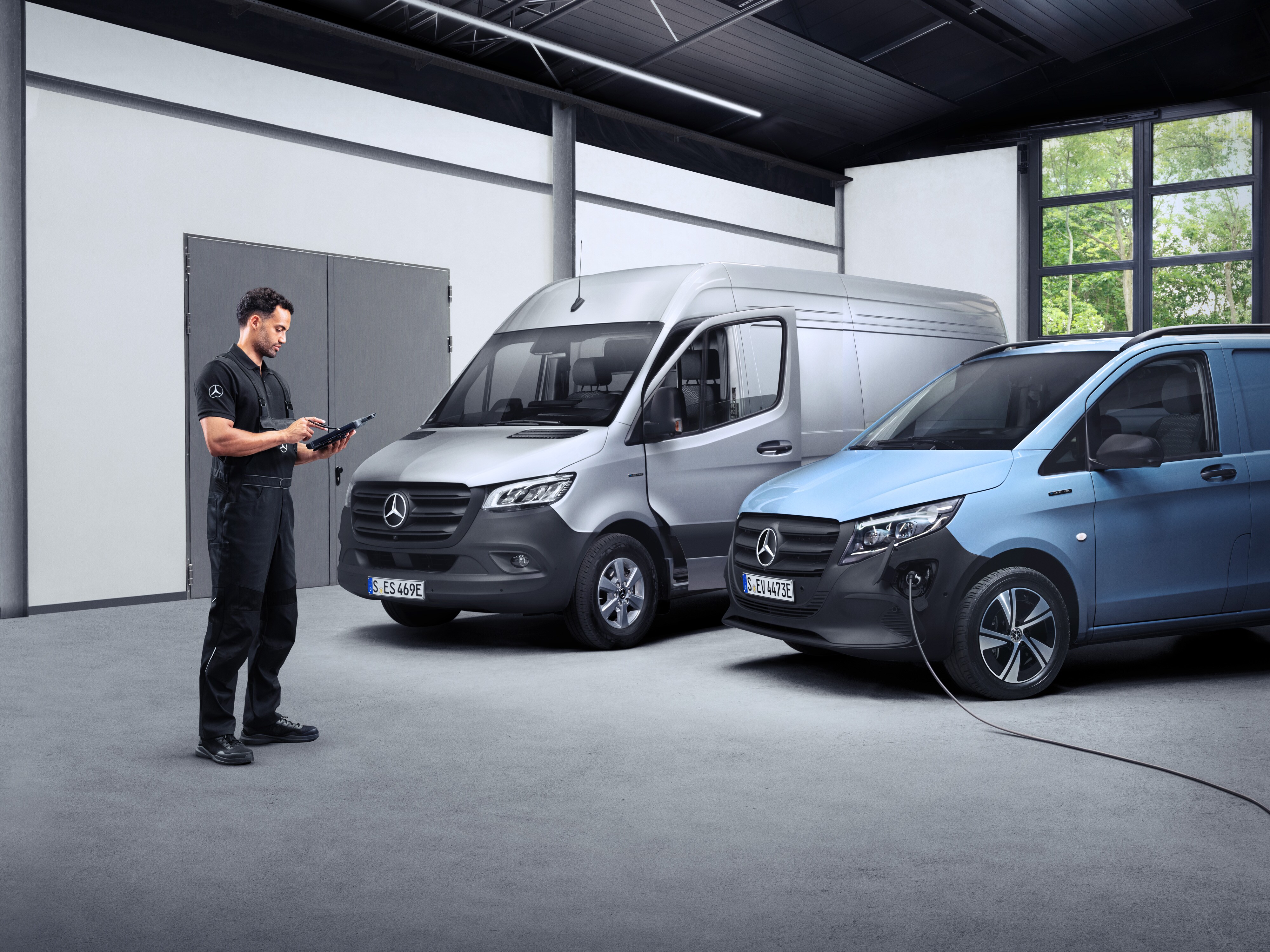 ServiceCare | Mercedes-Benz Transporter. Ein Techniker steht vor Mercedes-Benz Transportern in einer Halle – abgesichert mit dem Mercedes Service Paket.
