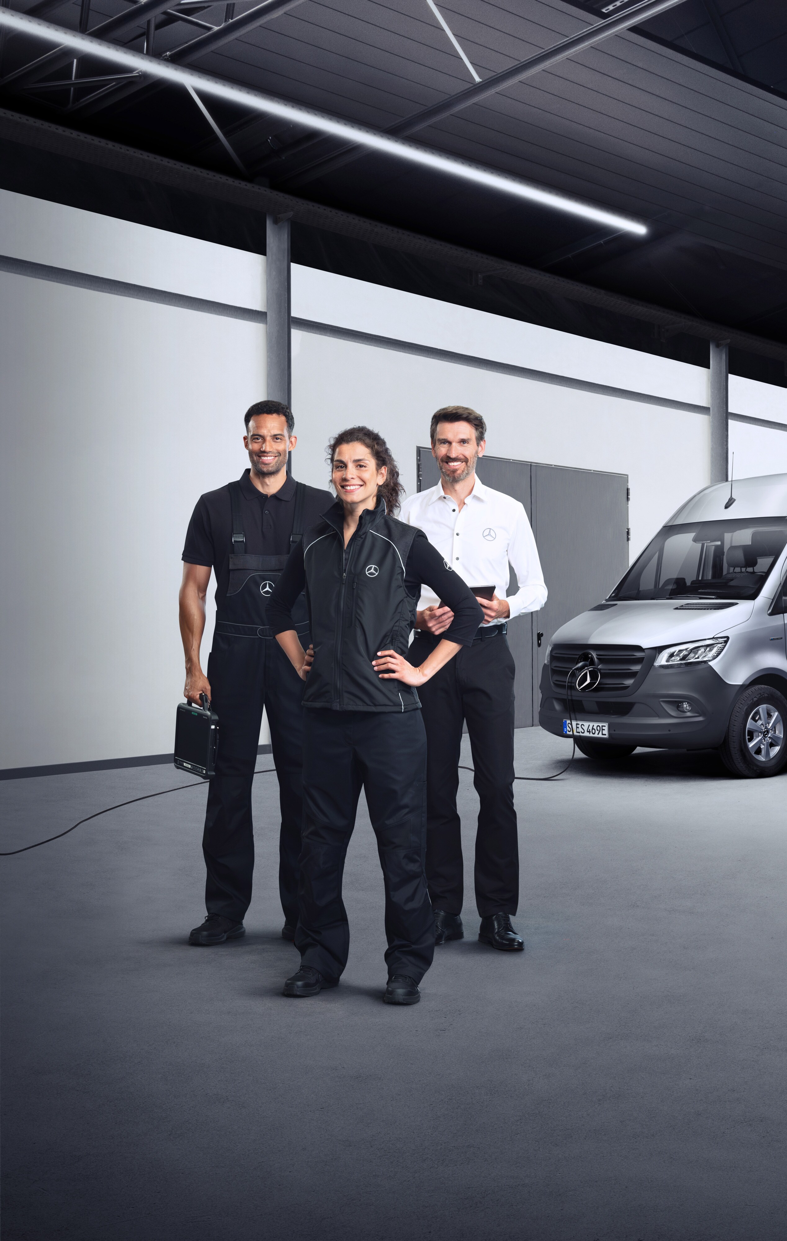 Elektrofahrzeug-Service | Mercedes-Benz Transporter. Drei Mitarbeiter vor einem elektrischen Mercedes-Benz Sprinter mit angeschlossenem Ladekabel.