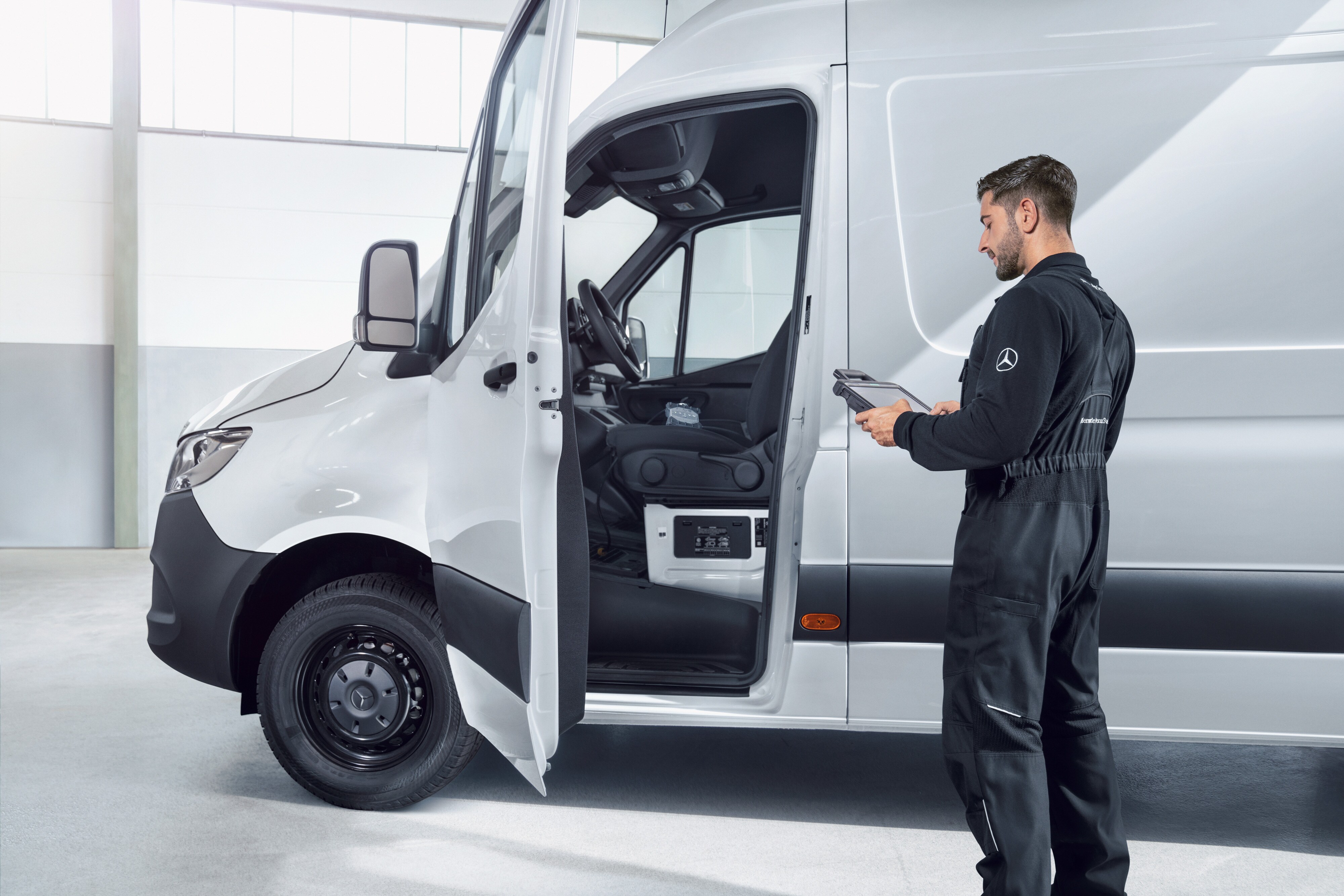 Fleet Services | Mercedes-Benz Transporter. Ein Techniker im Overall überprüft einen weißen Mercedes-Benz Sprinter mit einem Tablet.