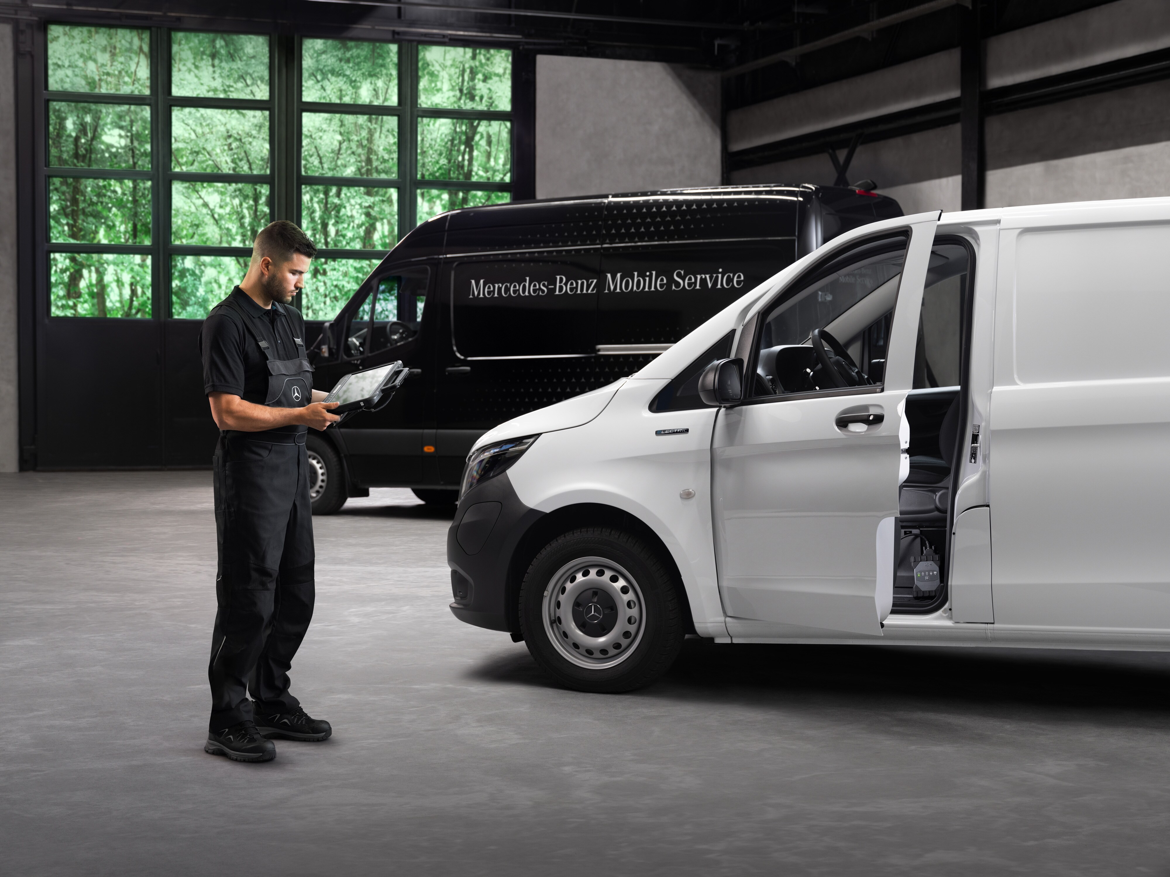 Mobile Service | Mercedes-Benz Transporter. Ein Techniker überprüft einen weißen Mercedes-Benz Vito in einer Werkstatt mit grauem Betonboden.